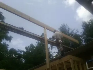Carpenter setting a ridge beam over a new addition frame — Ice Dam Removal by Roofing Brothers in Pattersonville