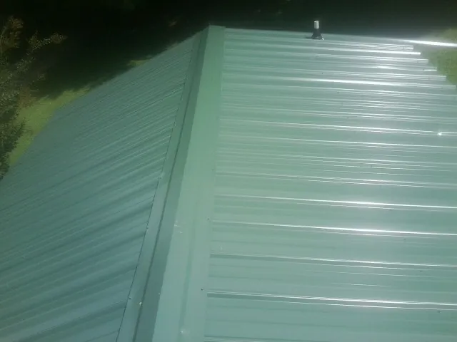 New green metal panels meeting at the ridge of a roof — Flat Roof Repair work by our crew in Pattersonville