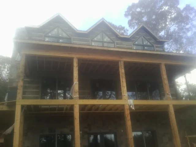 Dormers and porch framing on a large log home under construction — Roof Coating work by our crew in Pattersonville