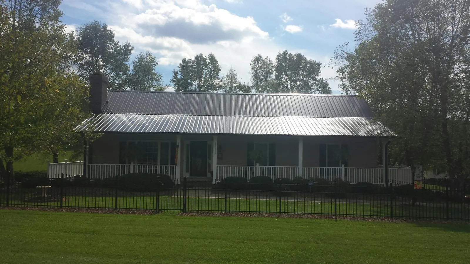 Gray metal roof on a brick ranch with a full width front porch — Gutter Guard Installation work by our crew in Pattersonville
