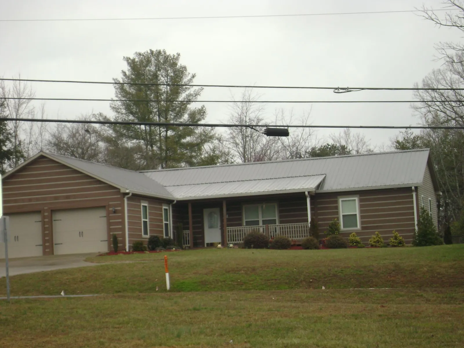 Gray metal roof on a log sided ranch home with a front porch in Pattersonville