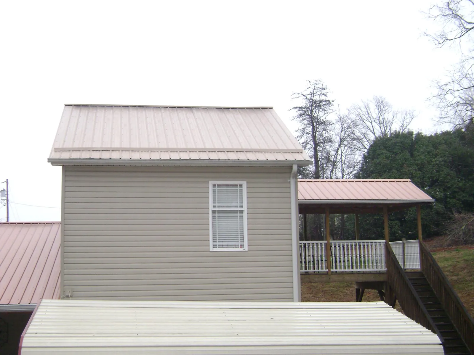 Tan metal roofs on a two story addition and attached porch, from a Roof Replacement job in Pattersonville