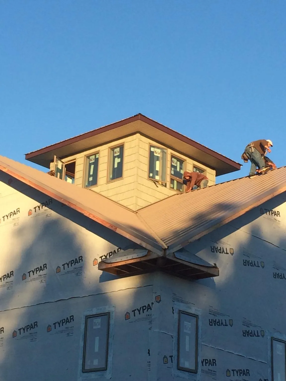 Roofers working around a rooftop cupola on a new metal roof at sunset — Roof Waterproofing in Pattersonville by Roofing Brothers